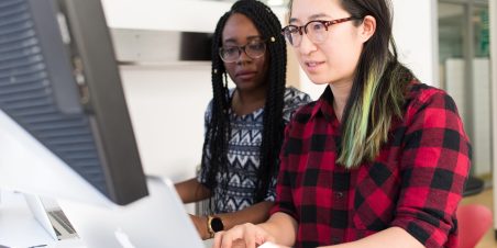 Photo: Two women working together at a computer.