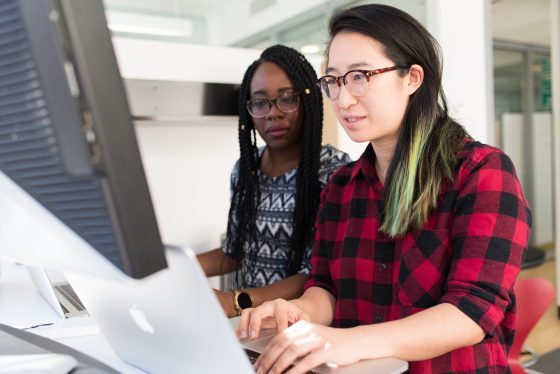 Photo: Two women working together at a computer.