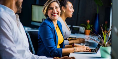 Photo: Woman in workforce smiling at office coworkers.