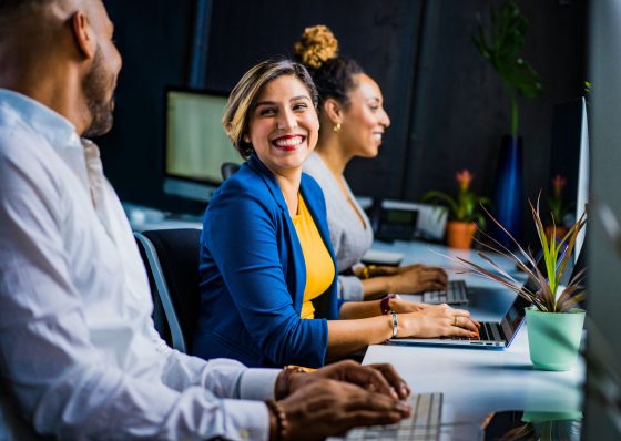 Photo: Woman in workforce smiling at office coworkers.