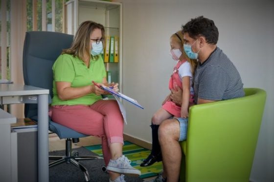 Photo: Case worker wearing a pandemic mask meeting with father and child also wearing pandemic masks for a services assessment