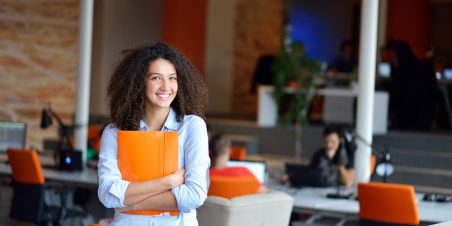 Woman holding orange binder at a office