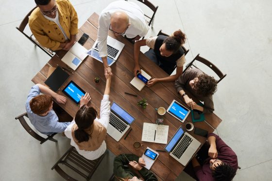 Team collaborating on devices around a table